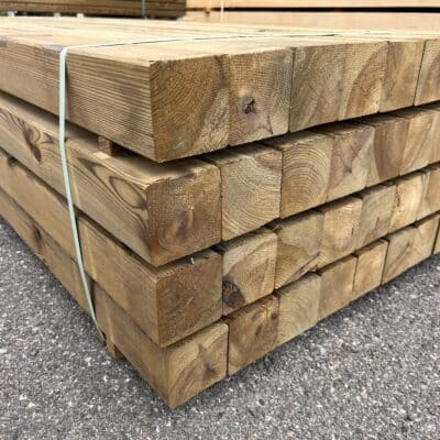 Poteaux en bois carrés traités autoclave empilés, matériaux de construction robustes pour l'extérieur.
