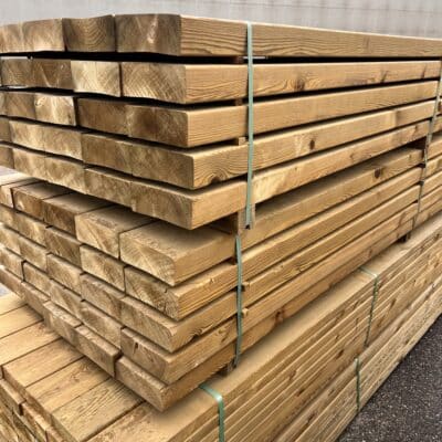 Planches de bois de charpente empilées et attachées avec des sangles vertes pour la construction.