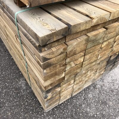 Empilement de planches en bois traité liées par une sangle pour la construction d'une terrasse.